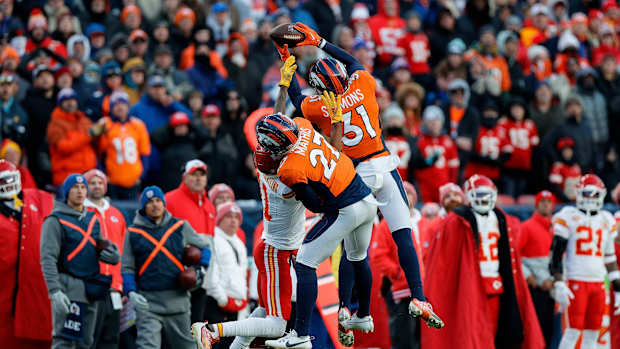 Denver Broncos safety Justin Simmons (31) intercepts a pass intended for Kansas City Chiefs wide receiver Marquez Valdes-Scantling (11) as cornerback Damarri Mathis (27) defends in the fourth quarter at Empower Field at Mile High.